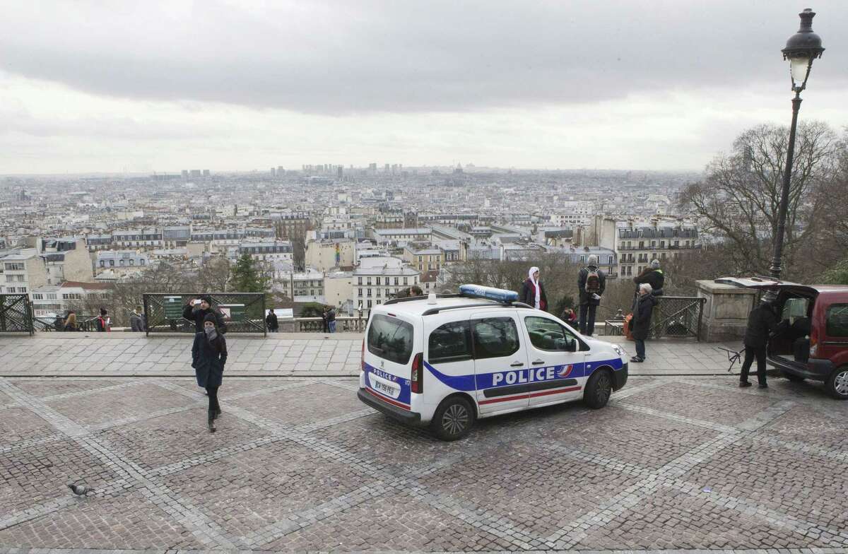 French police car parks outside the Sacre Coeur basilica at Montmartre district, in Paris,, Monday, Jan. 12, 2015. France on Monday ordered 10,000 troops into the streets to protect sensitive sites after three days of bloodshed and terror, amid the hunt for accomplices to the attacks that left 17 people and the three gunmen dead. (AP Photo/Jacques Brinon)