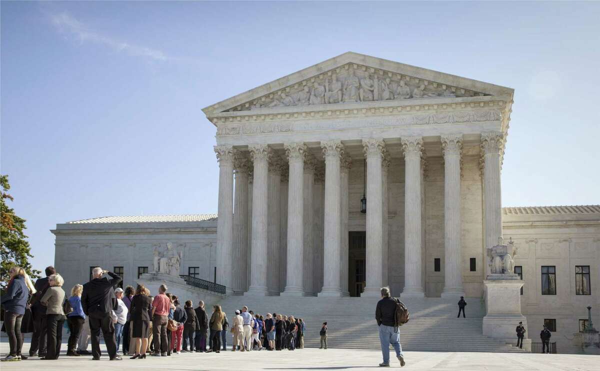 In this Oct. 6, 2014 photo, people wait to enter the Supreme Court in Washington. The Supreme Court could put the brakes on the Obama administration’s growing crackdown against companies facing claims of discrimination against women, minorities and other protected groups.