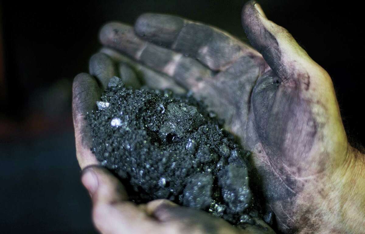Superintendent Jackie Ratliff, a coal miner of 25 years, holds coal running through a processing plant in Welch, W.Va.