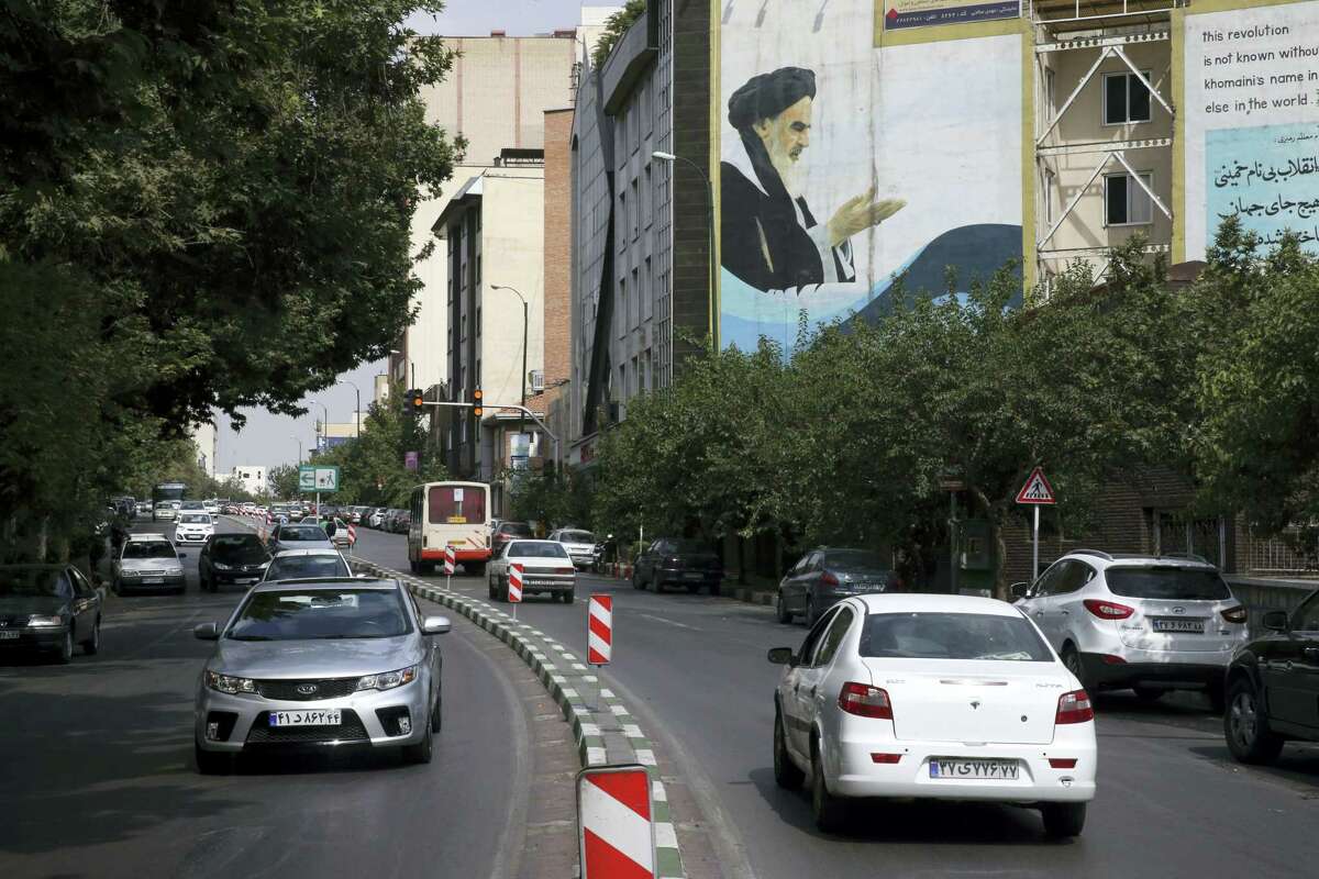 Cars drive past a painting of late Iranian revolutionary founder Ayatollah Khomeini at Bahonar street in northern Tehran, Iran. Chevrolet, the U.S. car brand once advertised as the “Heartbeat of America,” won’t be rolling new models through the streets of Iran anytime soon despite the recent lifting of sanctions under a nuclear deal with world powers.