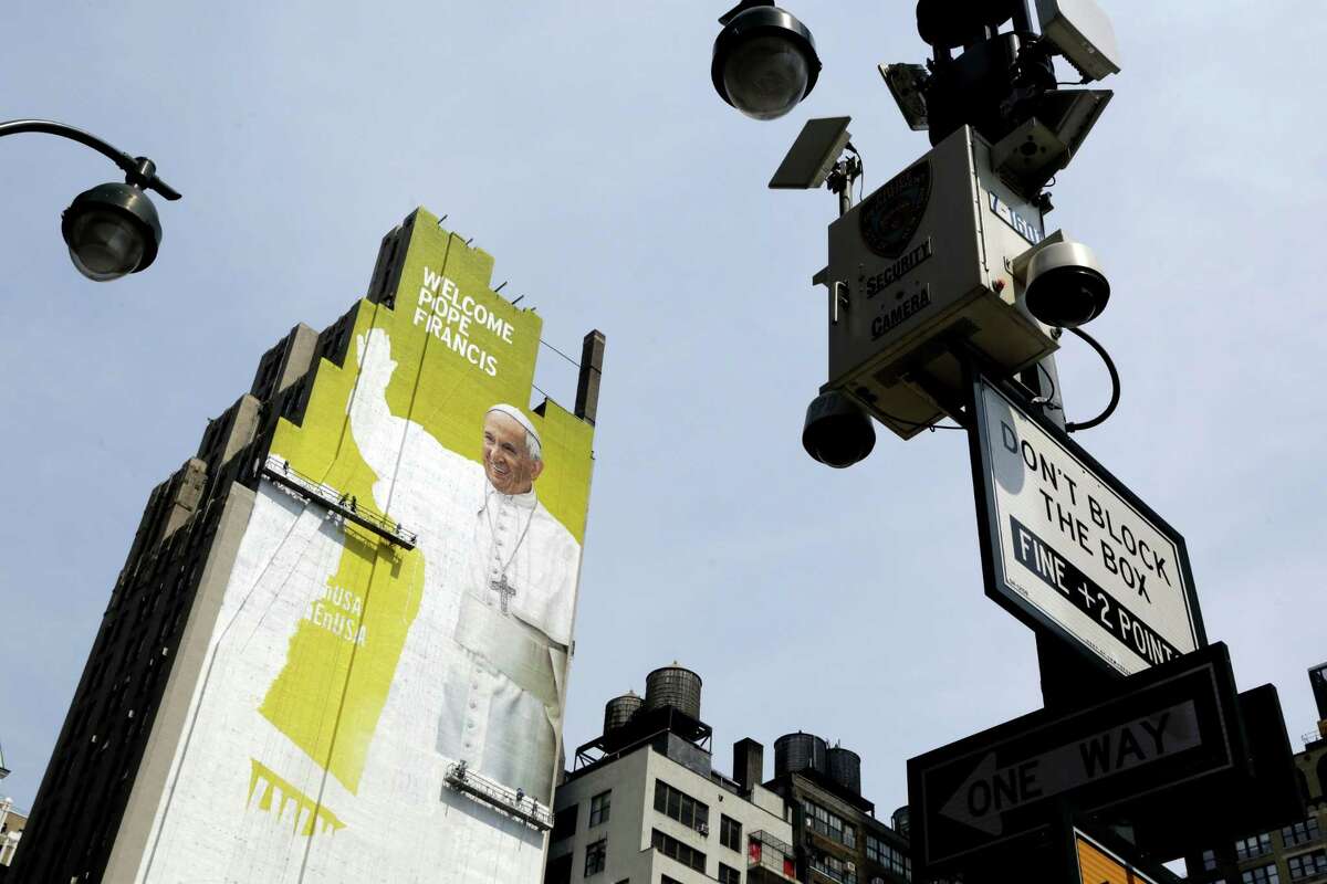 In this Aug. 30, 2015 file photo, sign painters work on a portrait of Pope Francis on the side of a New York City office building as some surveillance cameras operated by the New York City Police Department can be seen on lamp posts at either side. New York Police Commissioner William Bratton says local, state and federal law enforcement face an ìunprecedented challenge,î ensuring the pontiffís safety as he address over 160 heads of state at the United Nations, presides over a 9/11 memorial service, rides through Central Park and celebrates Mass at Madison Square Garden.