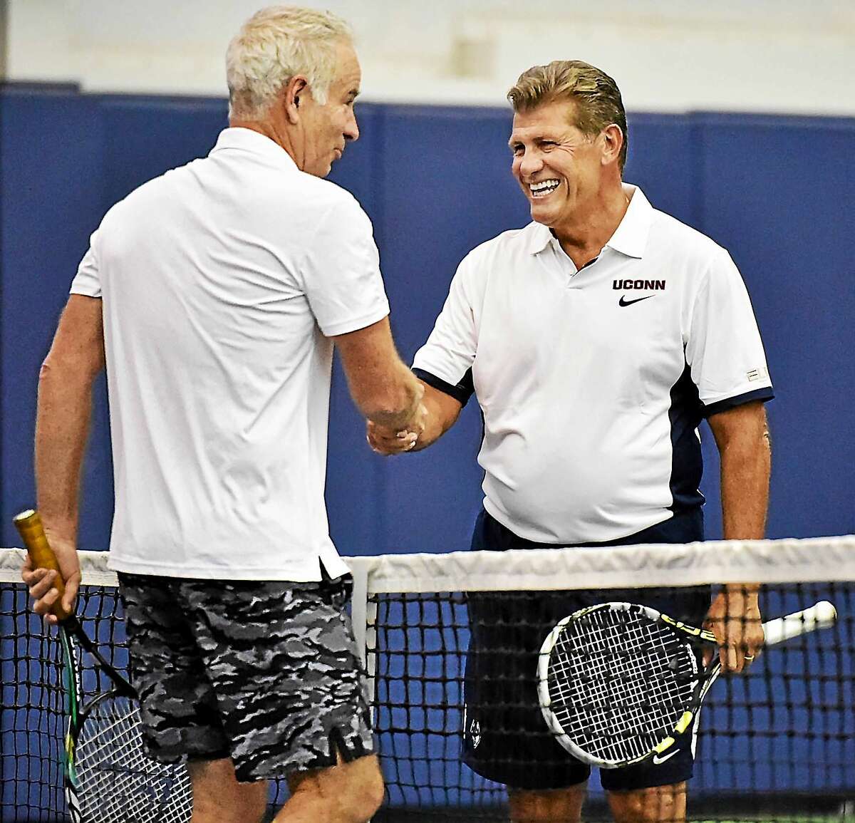 UConn women’s basketball coach Geno Auriemma greets John McEnroe at the net following their match at the Cullman-Heyman Tennis Center at the Connecticut Open on Friday in New Haven.