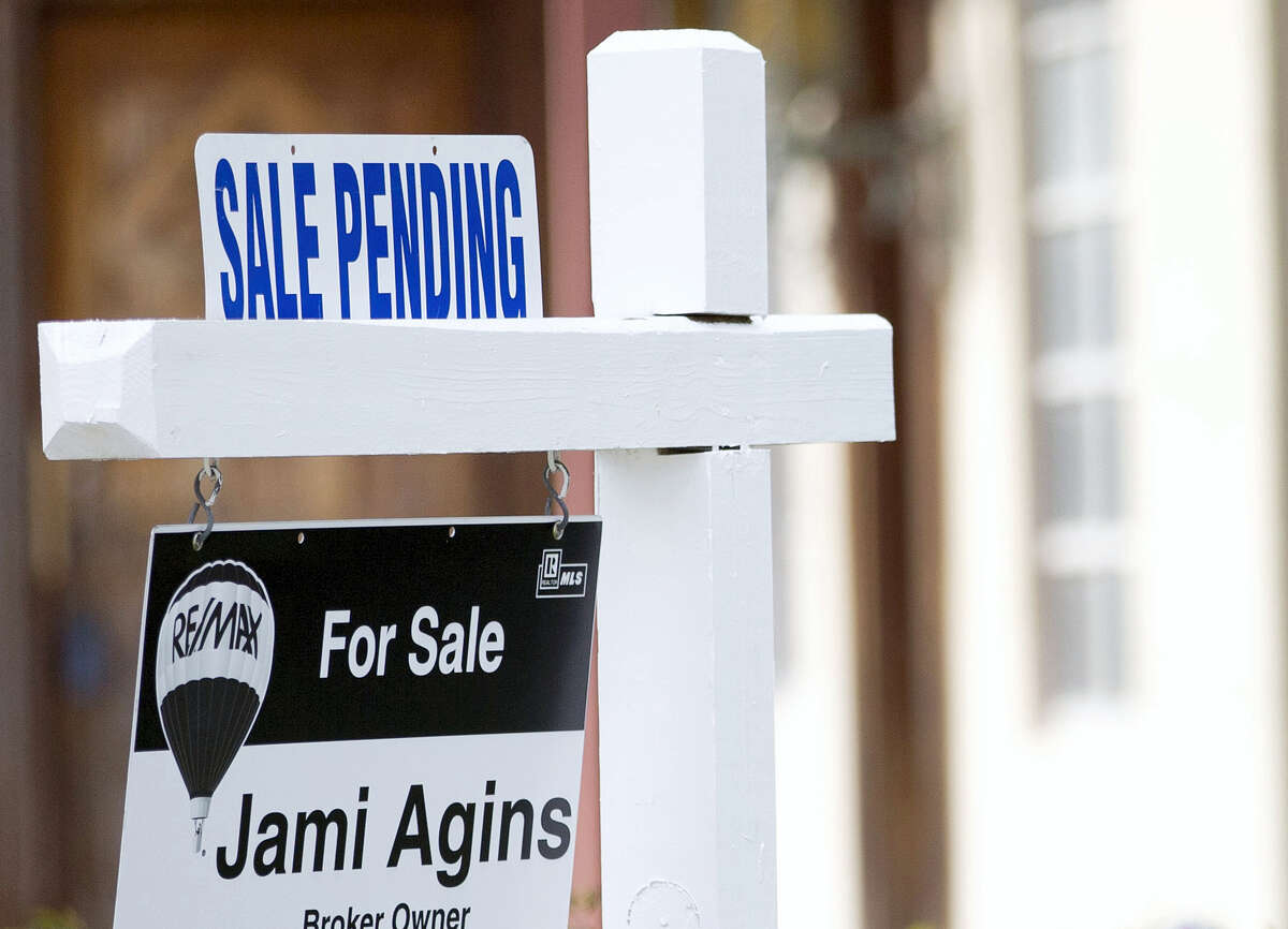 A “Sale Pending” sign sits atop a realty sign outside a home for sale in Surfside, Fla.