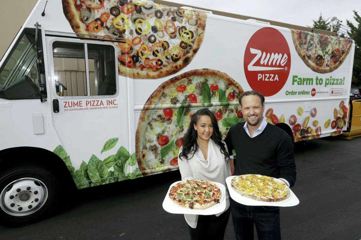 In this Monday, Aug. 29, 2016 photo, CEO and co-founder Julia Collins, left, and co-founder Alex Garden pose for a photo in front of one of the company’s delivery trucks at Zume Pizza in Mountain View, Calif. The startup, which began delivery in April, is using intelligent machines to grab a slice of the multi-billion-dollar pizza delivery market. Zume is one of a growing number of food-tech firms seeking to disrupt the restaurant industry with software and robots that let them cut costs, speed production and improve worker safety.
