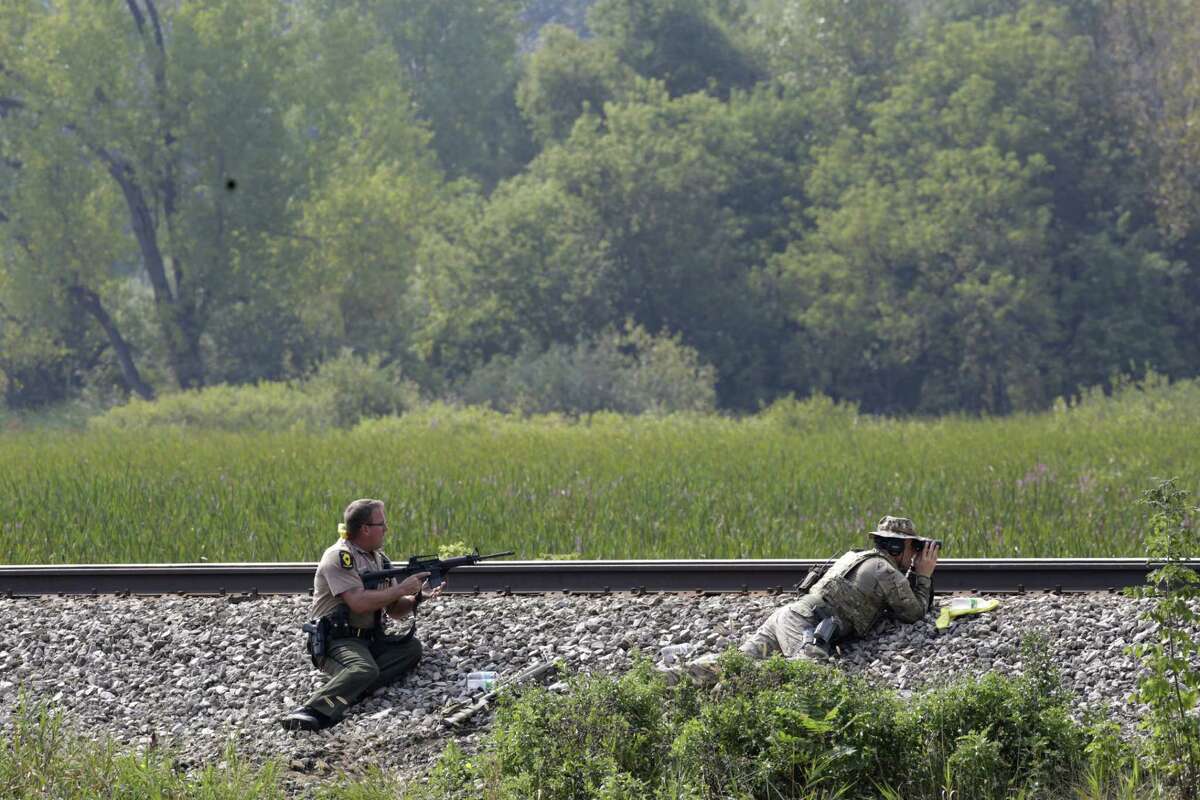 Police officers patrol a swampy area in Fox Lake, Ill., during a manhunt after an officer was shot and killed while pursuing a group of suspicious men, Tuesday, Sept. 1, 2015. Authorities in Fox Lake, 55 miles north of Chicago, have notified a number of other law enforcement agencies to ask for assistance, including the FBI, which is sending agents to help in the investigation.