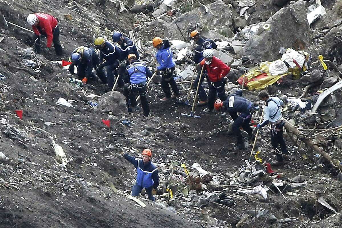 FILE - In this March 26, 2015 file photo, rescue workers work on debris of the Germanwings jet at the crash site near Seyne-les-Alpes, France. The co-pilot of Germanwings Flight 4525 tried a controlled descent on the previous flight that morning to Barcelona before the plane crashed into a mountainside in March on its way back to Germany, French air accident investigators said in a new report released Wednesday May, 6, 2015.