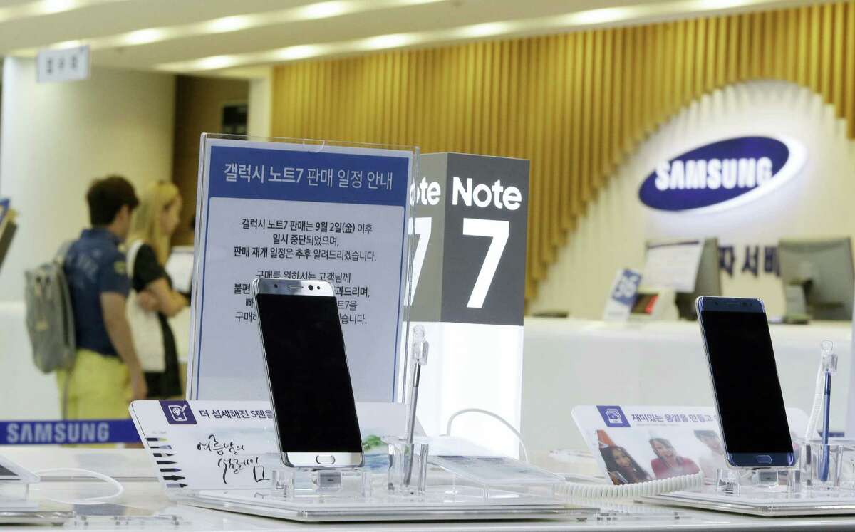 In this Sunday, Sept. 11, 2016 photo, customers wait for recall of their Samsung Electronics Galaxy Note 7 smartphones as powered-off Galaxy Note 7 smartphones are displayed at the company’s service center in Seoul, South Korea. Samsung on Tuesday, Sept. 13, 2016, plans to issue a software update for its recalled Galaxy Note 7 smartphones that will prevent them from overheating by limiting battery recharges to under 60 percent.