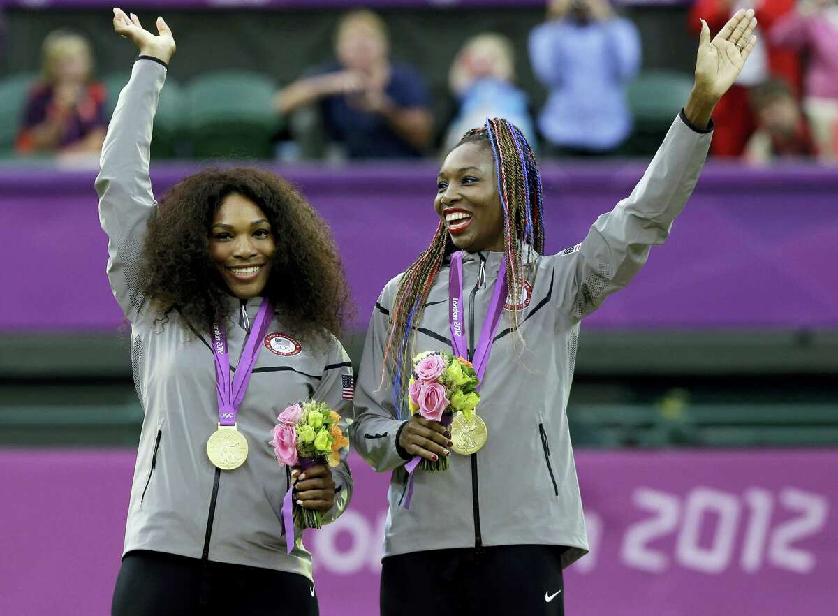 In this photo from the 2012 London Summer Olympics, Serena Williams, left, and Venus Williams of the celebrate on podium after receiving their gold medals in women’s doubles. The winningest team in Olympic tennis history has entered the doubles draw at this week’s Italian Open to kick off their preparations for the Rio de Janeiro Games.