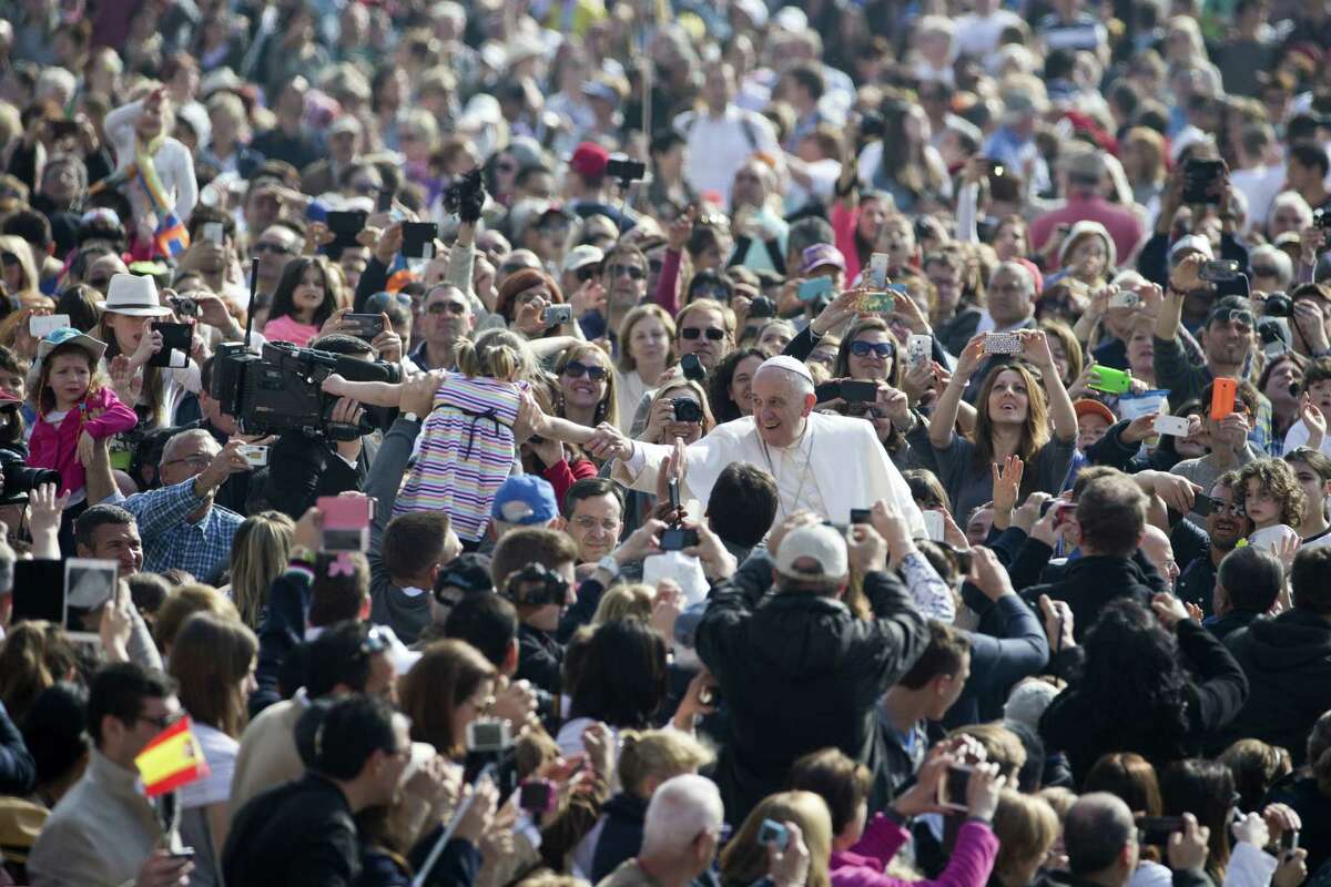 FILE - In this Wednesday, April 15, 2015 file photo, Pope Francis, center, greets a child as he arrives for his weekly general audience, in St. Peter’s Square, at the Vatican. When Pope Francis visits the United States this fall, he can expect the same rock-star adulation that greets him wherever he goes. But his positions on hot-button issues such as the death penalty and climate change could quickly set the stage for conflict. That may explain why Francis has been clearing the decks on a host of less high-profile matters of contention that could also have marred the visit.