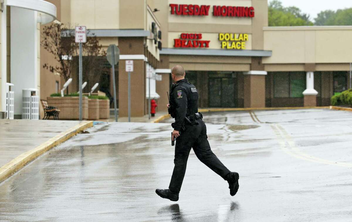A police officer with his gun drawn runs for cover as Eulalio Tordil, 62, a suspect in three fatal shootings in the Washington, D.C., area is taken into custody nearby, in Silver Spring, Md., Friday, May 6, 2016. Tordil is an employee of the Federal Protective Service, which provides security at federal properties. He was put on administrative duties in March after a protective order was issued against him.