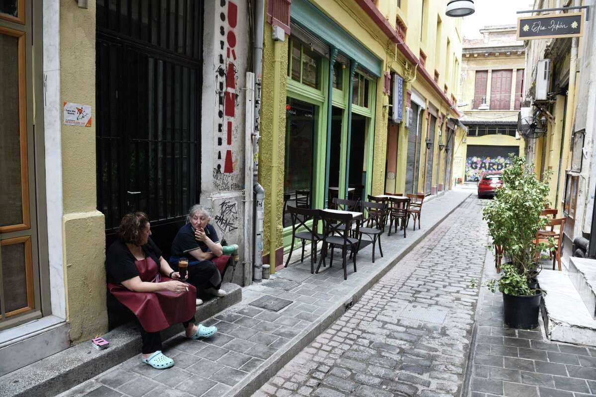 Employees of a restaurant talk on an empty street in the northern Greek port city of Thessaloniki, Tuesday. Greek Finance Minister Yanis Varoufakis confirmed that the country will not make its payment due later to the International Monetary Fund. Capital controls began Monday and will last at least a week, an attempt to keep the banks from collapsing in the face of a nationwide bank run.