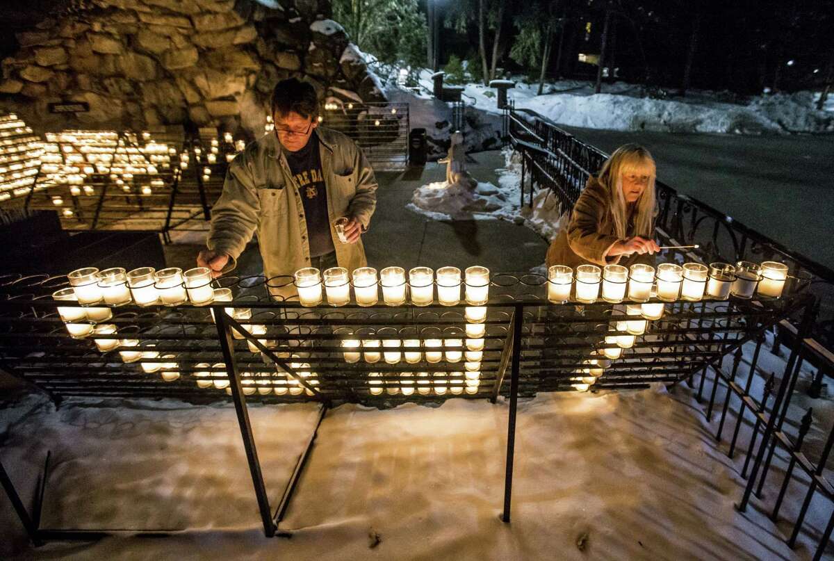 William Michalski and his wife Rose Michalski, of South Bend, light votives that spell out "TED" as the visit the Grotto of Our Lady of Lourdes on the campus of the University of Notre Dame following the death of former Notre Dame president Rev. Theodore M. Hesburgh, age 97, on Friday, Feb. 27, 2015, in South Bend, Ind. Rose Michalski has worked at Notre Dame for 31 years. (AP Photo/South Bend Tribune, Robert Franklin)