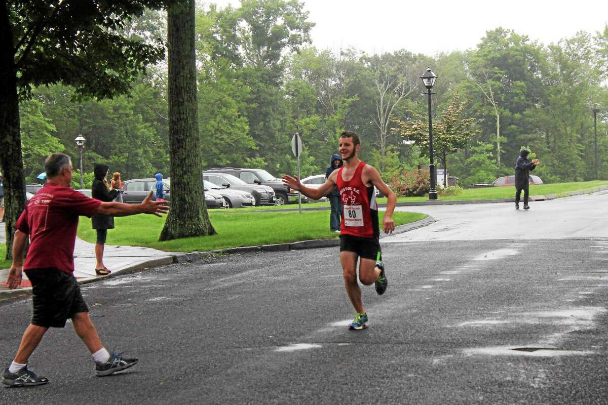 John Neston -- Register-Citizen Max Girouard of Bristol is congratulated at the fiinished line for winning the 5K race.