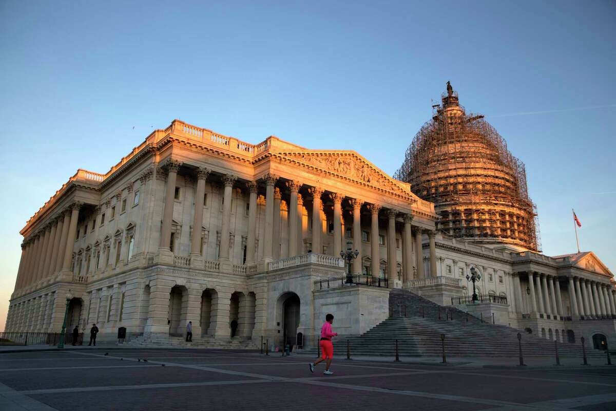 In this Oct. 22, 2015, file photo, a jogger runs past the House side of the Capitol at sunrise on Capitol Hill in Washington. A majority of Americans think government spending cuts are so important that it would be worth a government shutdown to achieve them, according to a new Associated Press-GfK poll. And there’s also a major partisan divide on how Congress should handle the debt ceiling talks