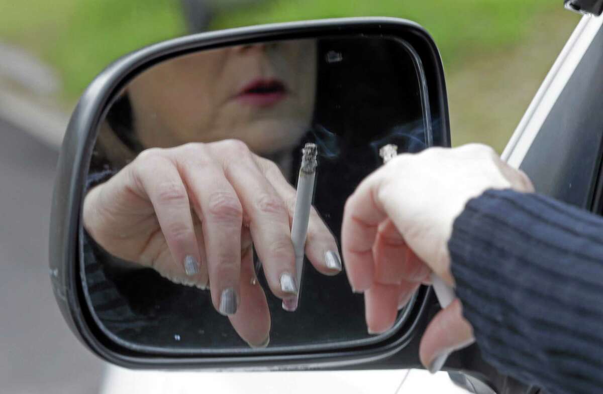File — A woman smokes a cigarette while sitting in her truck in Hayneville, Ala.