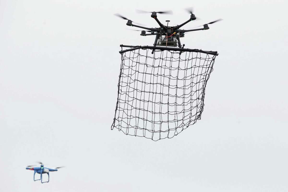 FILE - In this Monday Feb. 9, 2015 file photo, a drone Interceptor MP200, top, prepares to catch a drone DJI Phantom 2 with a net during a demonstration flight in La Queue-en-Brie, east of Paris, France. Paris police say they spotted at least five drones flying over the French capital overnight Tuesday Feb. 24, 2015, and an investigation is under way into who was flying them and why. Franceís BFM television reported that they were seen flying over the Eiffel Tower, the Louvre Museum and the American Embassy, among other locations. (AP Photo/Francois Mori, File)