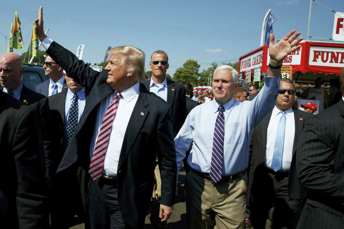 Republican presidential candidate Donald Trump, center left, waves as he walks with vice presidential candidate Gov. Mike Pence, R-Ind., center right, during a visit to the Canfield Fair on Sept. 5, 2016, in Canfield, Ohio.
