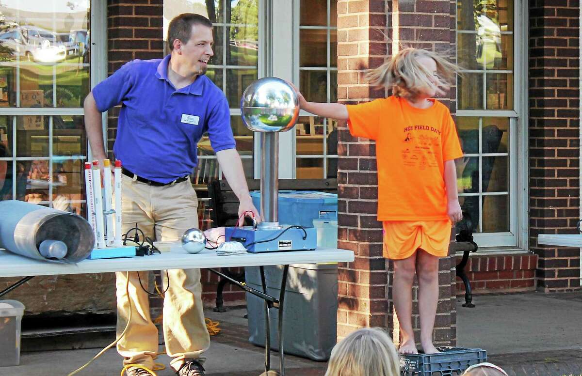 PHOTO BY JOHN NESTOR Dan Butterworth, The Childrens Museumís education program coordinator, entertained at the kickoff of the Harwinton Public Library's summer reading program Wednesday night. Highlights included making some volunteersí hair stand on end with electric currents, light tubes that glowed like light sabers thanks to a Tesla Coil and an experiment that illustrated how Franklin made the case that all houses and barns should have a lightning rod.