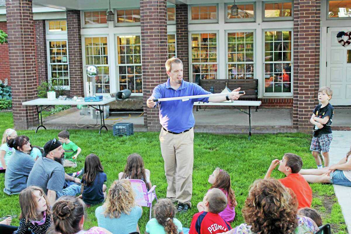 PHOTO BY JOHN NESTOR Dan Butterworth, The Childrens Museumís education program coordinator, entertained at the kickoff of the Harwinton Public Library's summer reading program Wednesday night. Highlights included making some volunteersí hair stand on end with electric currents, light tubes that glowed like light sabers thanks to a Tesla Coil and an experiment that illustrated how Franklin made the case that all houses and barns should have a lightning rod.