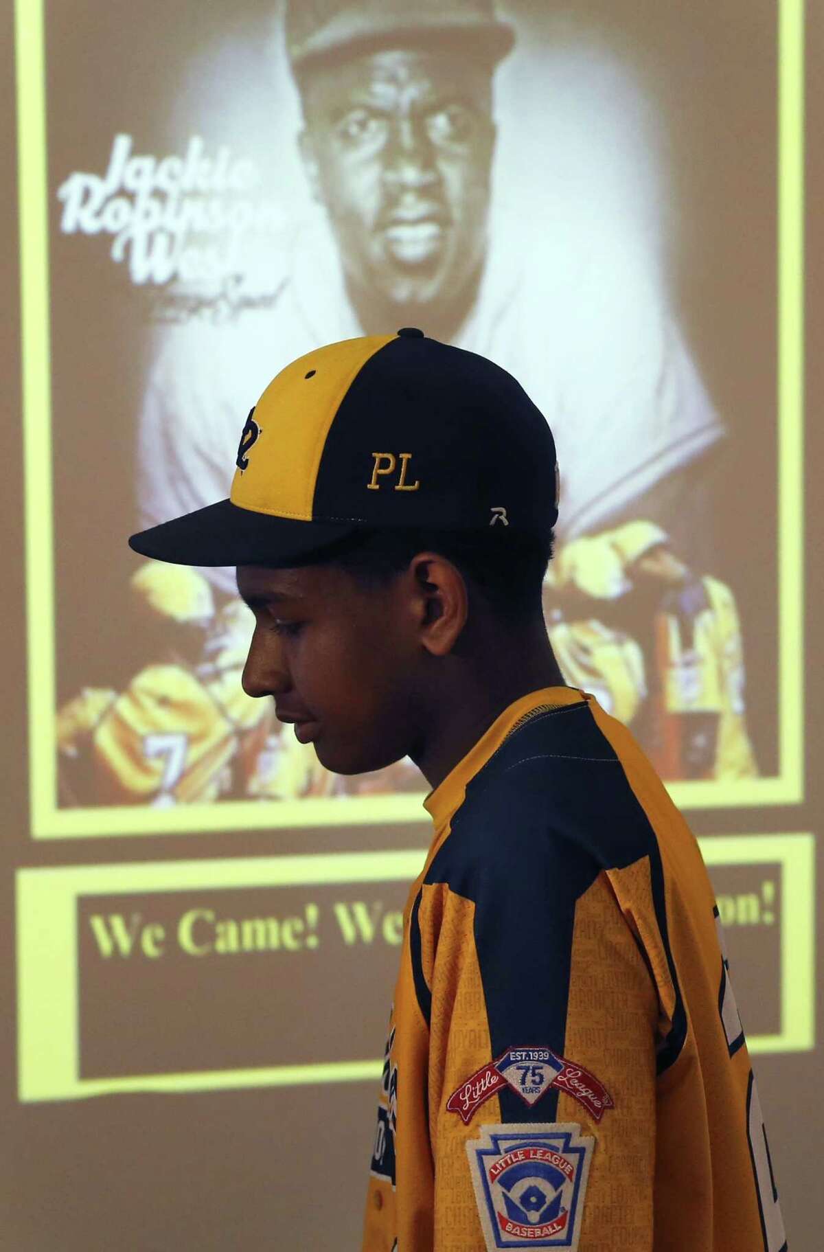 Jackie Robinson West Little League player Prentiss Luster walks past a projected image of Jackie Robinson after team attorney Victor Henderson addressed reporters at a news conference Wednesday in Chicago.