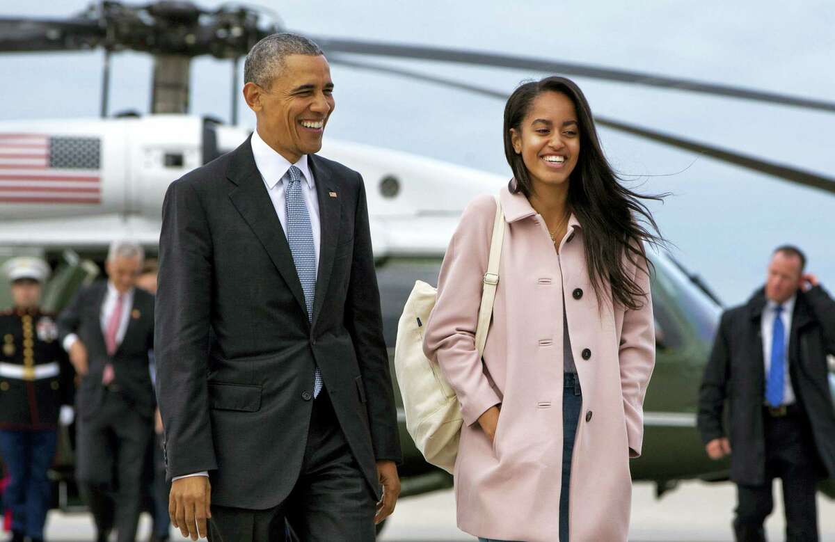 In an April 7, 2016 photo, President Barack Obama jokes with his daughter Malia Obama as they walk to board Air Force One from the Marine One helicopter, as they leave Chicago en route to Los Angeles.