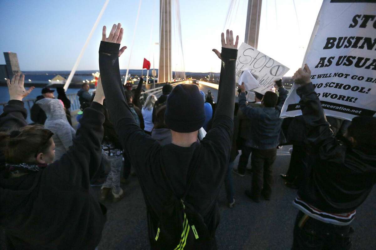Protesters hold up their hands and signs on the cable bridge Feb. 21, 2015, during a protest stemming from the officer involved shooting death of Antonio Zambrano-Montes.
