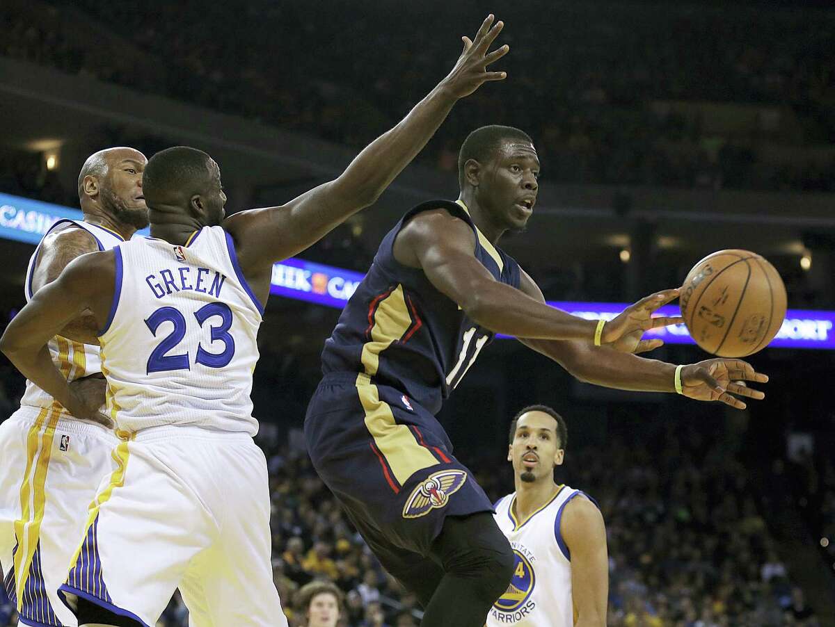 The Pelicans’ Jrue Holiday, right, passes away from the Warriors’ Draymond Green during a game last season.