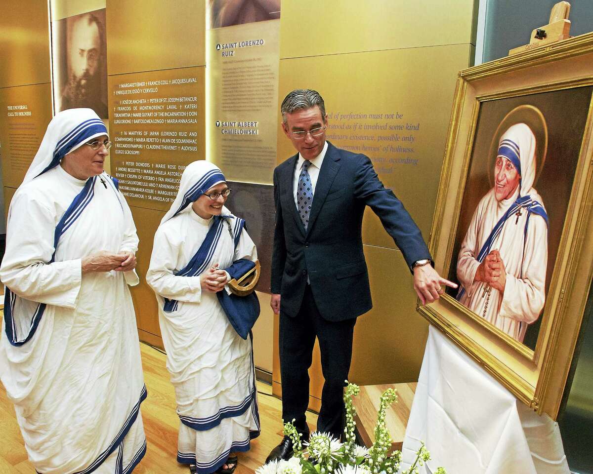 Artist Chas Fagan shows his portrait of Mother Teresa to two members of her order, the Missionaries of Charity.