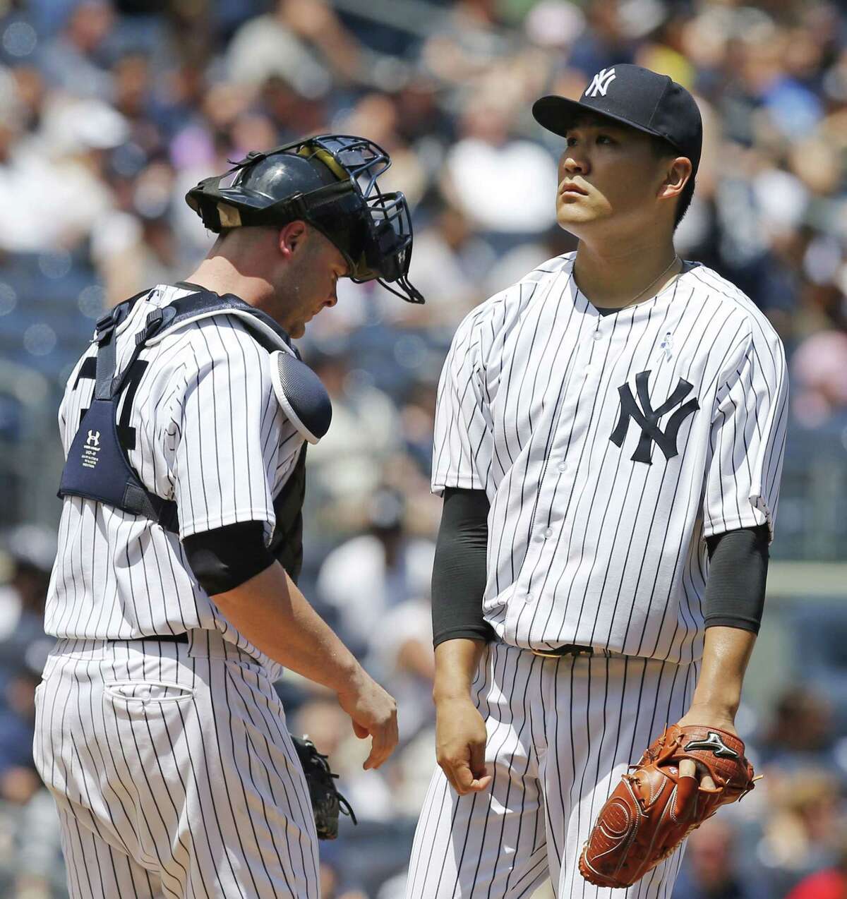 Yankees catcher Brian McCann, left, joints starting pitcher Masahiro Tanaka on the mound as Tanaka reacts after allowing a second-inning, two-run, single to Victor Martinez on Sunday.