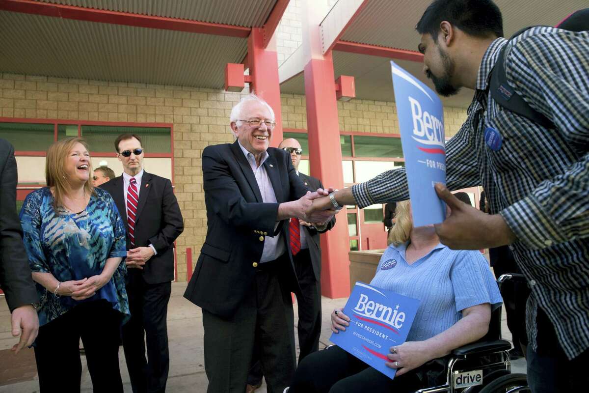 Democratic presidential candidate Sen. Bernie Sanders, I-Vt., center, shakes hands with voters as his wife, Jane, left, watches at a caucus site, Saturday, Feb. 20, 2016, in Las Vegas.