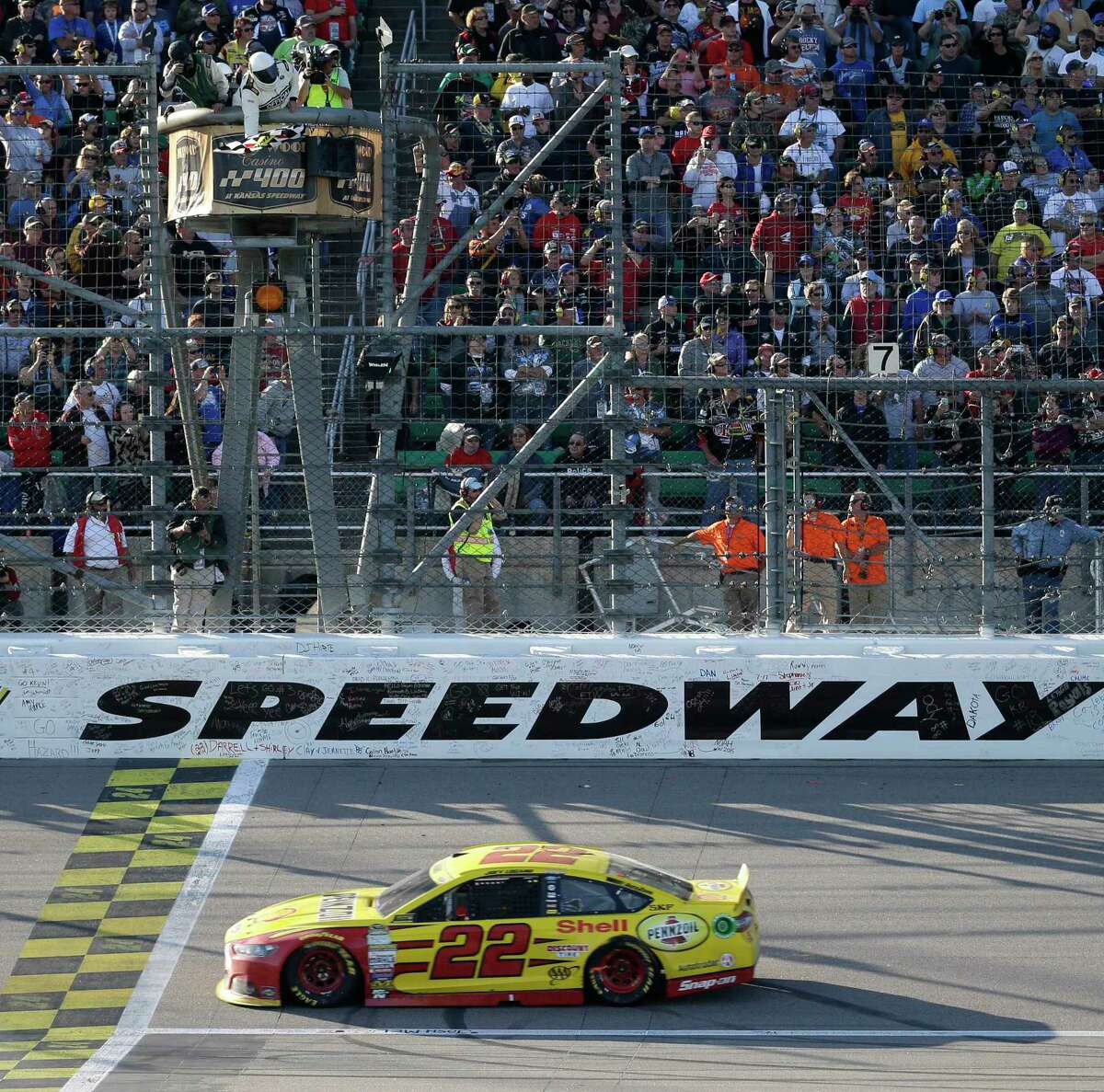 Joey Logano takes the checkered flag to win at Kansas Speedway in Kansas City, Kan., on Sunday.