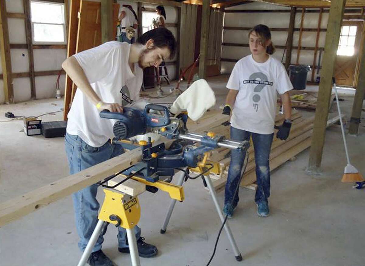 In this July 23, 2013 photo released by Ben's Lighthouse, Trystan Wagner uses a table saw to make a cut during the group's building project after tornadoes caused destruction in Moore, Okla. The annual service trip is run by Benís Lighthouse, a nonprofit founded to help children from Newtown, Conn., recover from the December 2012 massacre at Sandy Hook Elementary School. The organization is named after 6-year-old victim Ben Wheeler. The third annual trip will be in July 2015 to help rebuild homes devastated in the previous yearís flooding. (Ben's Lighthouse/Jen Marlin via AP)