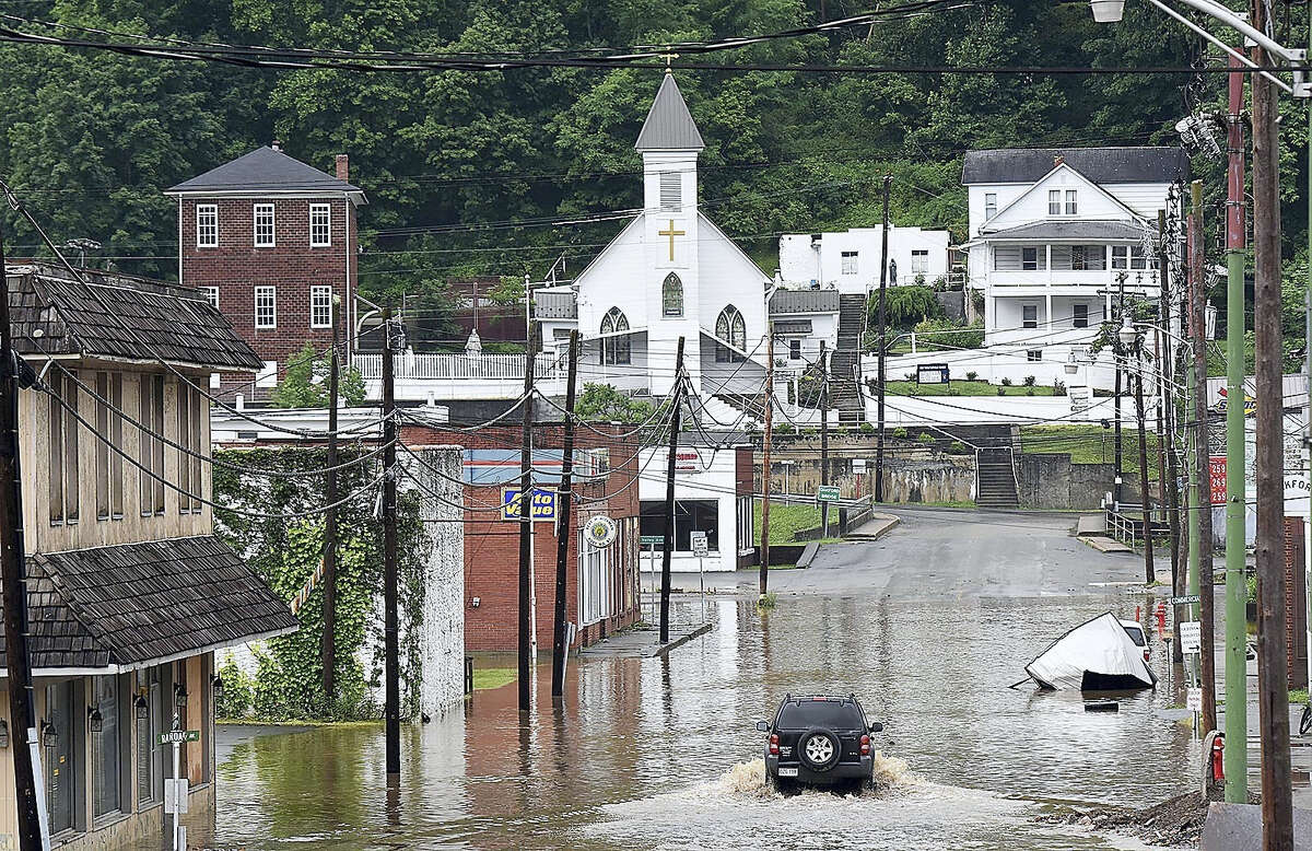 A vehicle makes a wake along the flooded Lower Oakford Ave. Friday, June 24, 2016, in Richwood, W.Va.