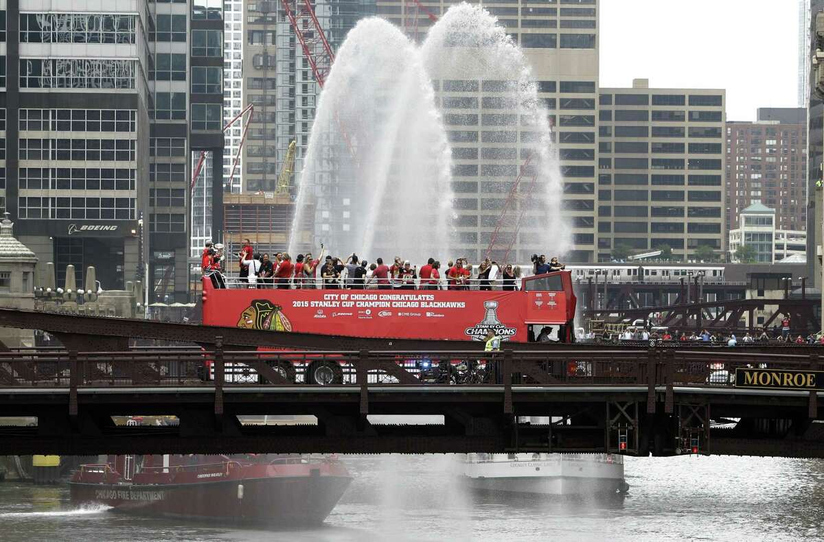 Chicago Blackhawks players, with the Stanley Cup, ride in an open-top bus across the Monroe Street Bridge over the Chicago River during a parade celebrating their Stanley Cup championship on Thursday.