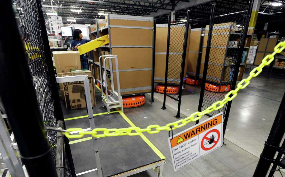 In this Feb. 13, 2015, file photo, a sign warns employees to stay away from an area where KIVA robotic transport units are in motion, during a media tour of the new Amazon fulfillment center in DuPont, Wash. The center is one of 50 around the country and three in the Puget Sound area that process and ship Amazon customer orders using a mix of robotic technology and human employees.