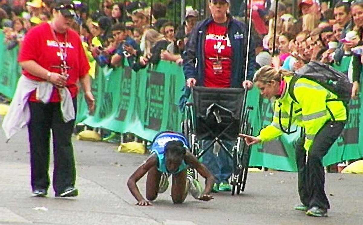 Austin Marathon volunteers rush to help elite runner Hyvon Ngetich after she collapsed to her knees near the finish line of the weekend race. Ngetich refused help and crawled across the finish line, taking third place.