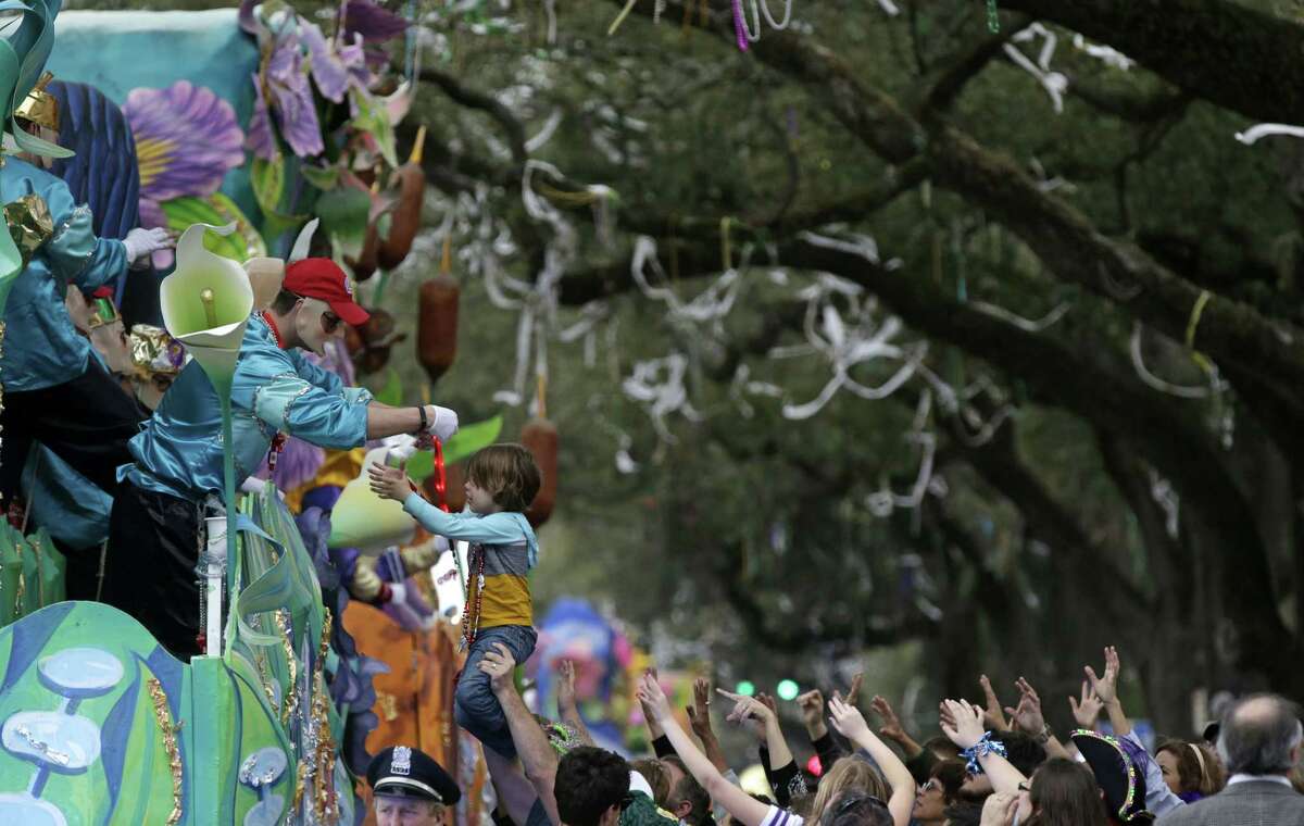 A float rider puts beads around the neck of a child during Krewe of Proteus Mardi Gras parade Monday in New Orleans. The day is known as Lundi Gras, the day before Mardi Gras.