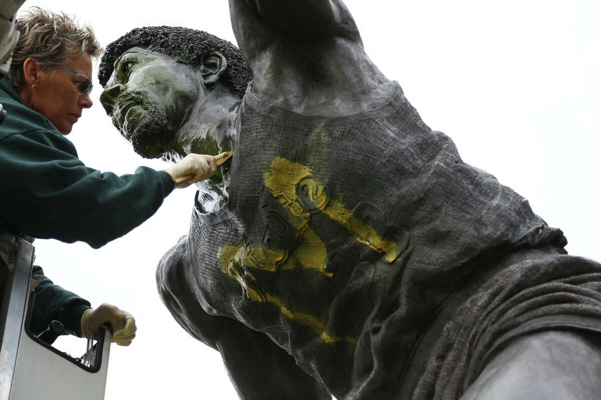 Tracy Harris cleans a statue of Earvin “Magic” Johnson on the campus of Michigan State University on Thursday.