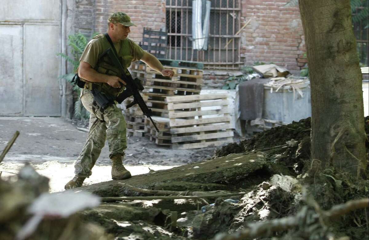 An armed police officer walks near a Zoo in Tbilisi, Georgia, Wednesday, June 17, 2015. Police in the ex-Soviet republic of Georgia reported that a tiger that broke loose after severe flooding at the Tbilisi Zoo was hiding at an abandoned factory when it mauled a man to death Wednesday before being shot by police. (AP Photo/Shakh Aivazov)