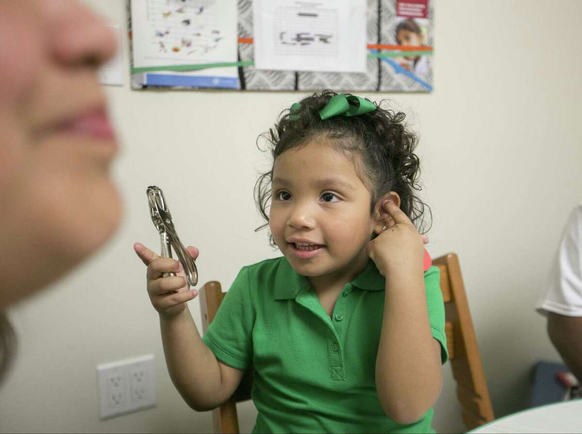 Angelica Lopez, 3, who is the recipient of an Auditory Brainstem Implant (ABI) holds a single-hole punch to help mark the sound of the word “punch,” as she receives oral recovery therapy from Debra Schader, an educational specialist at the USC-CHLA Center for Childhood Communication in Los Angeles.