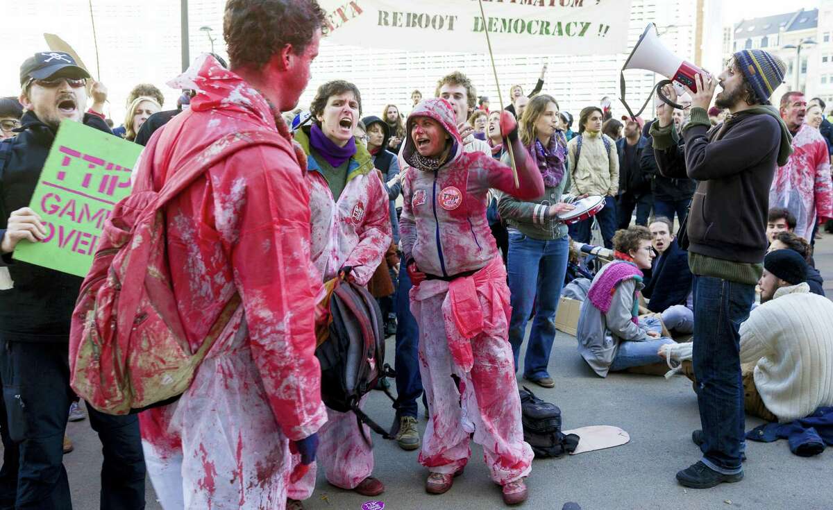 Demonstrators wearing paint splattered clothes protest outside of an EU-Canada summit at the European Council building in Brussels on Oct. 30, 2016. Canadian and EU officials, in a one-day summit, are to sign the Comprehensive Economic and Trade Agreement (CETA).