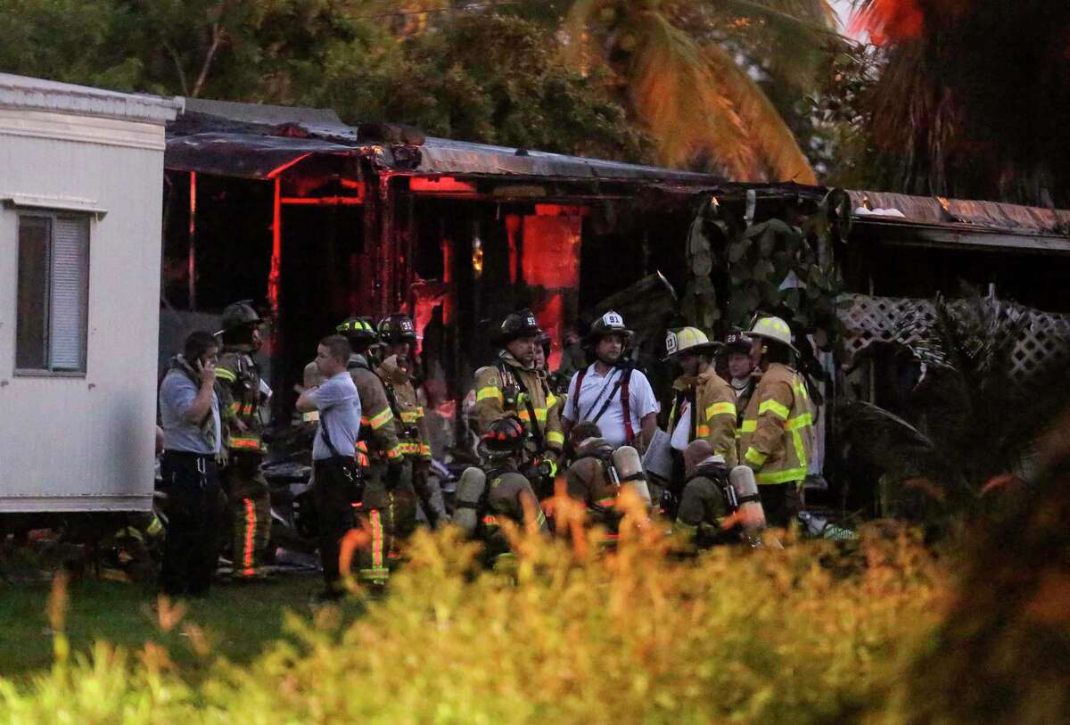 Firefighters gathrt after putting out a blaze caused when a small plane crashed into a mobile home park in Lake Worth, Fla., Tuesday, Oct. 13, 2015. The aircraft hit several homes at the Mar-Mak Colony Club.