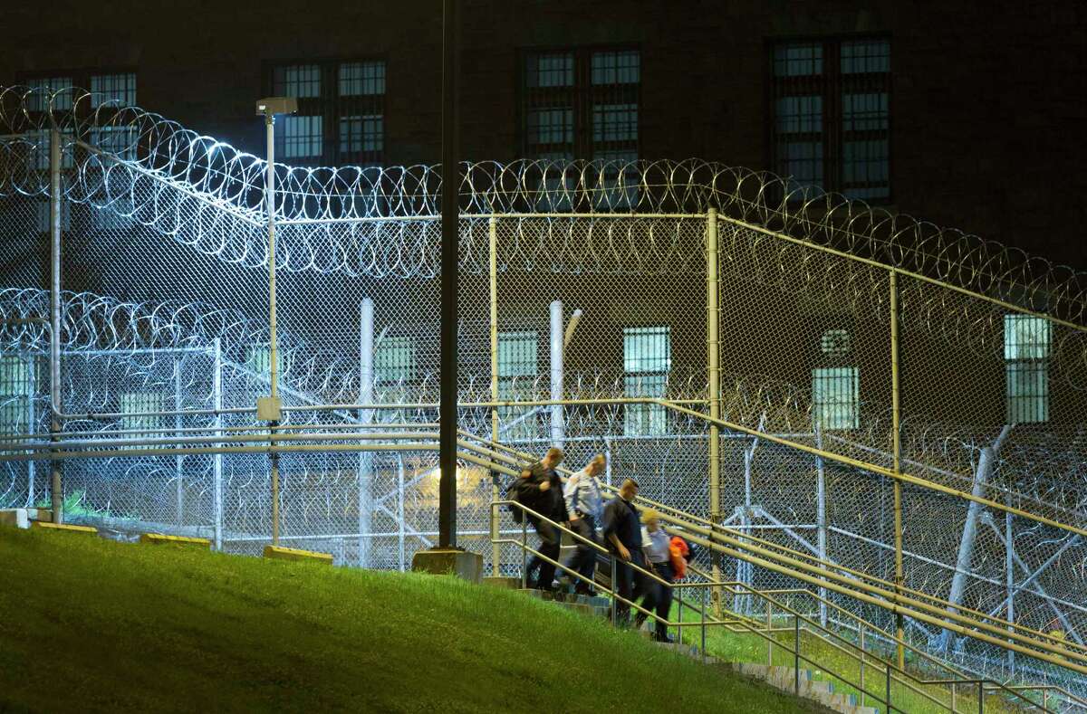 Corrections officers walk next to a fence covered in razor wire as they leave work at the Clinton Correctional Facility, Monday, June 15, 2015 in Dannemora, N.Y. State police say more than 800 law enforcement officers are pushing on in the hunt for convicted murderers David Sweat and Richard Matt 10 days after the two escaped from the maximum-security prison in rural New York. (AP Photo/Mark Lennihan)
