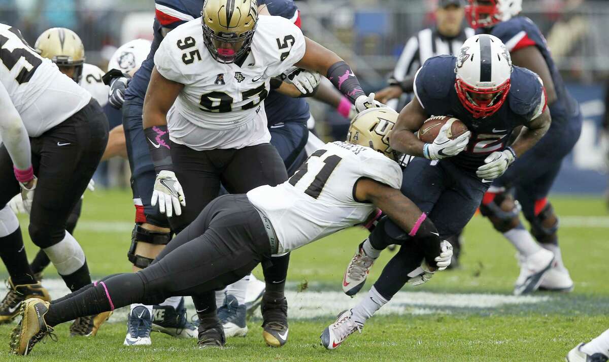 UConn running back Arkeel Newsome, right, looks to break a tackle during last week’s game against UCF.