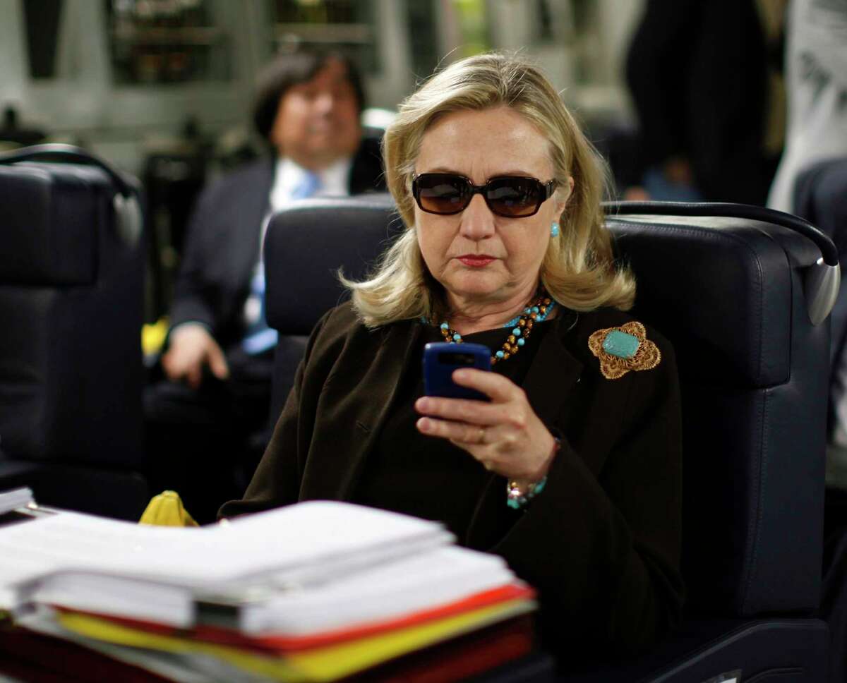 In this Oct. 18, 2011, file photo, then-Secretary of State Hillary Rodham Clinton checks her Blackberry from a desk inside a C-17 military plane upon her departure from Malta, in the Mediterranean Sea, bound for Tripoli, Libya. The private email server running in Clinton’s home basement when she was secretary of state was connected to the Internet in ways that made it more vulnerable to hackers, according to data and documents reviewed by The Associated Press.