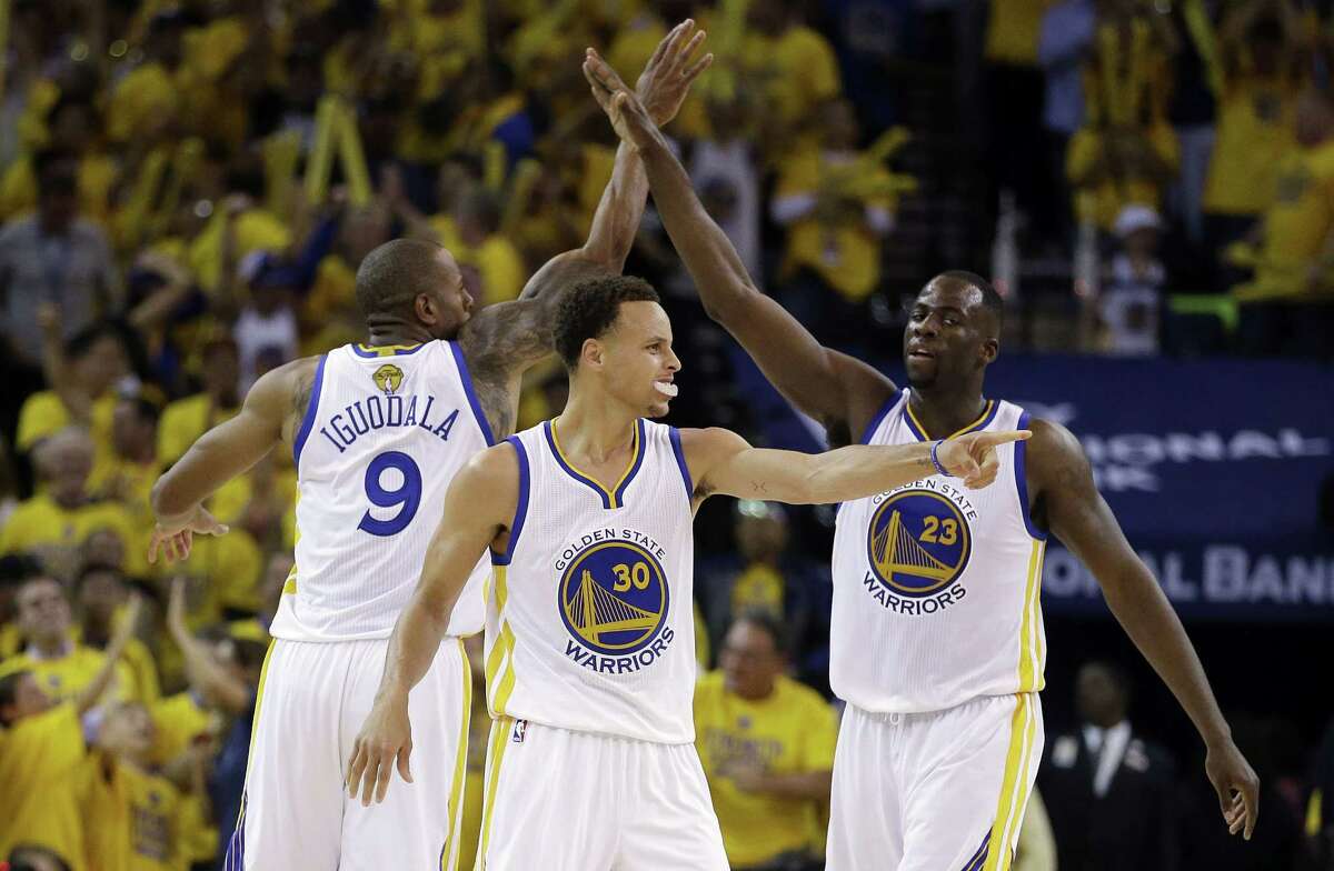 Warriors guard Stephen Curry, center, forward Andre Iguodala, left, and forward Draymond Green react during the second half of Game 5 of the NBA Finals on Sunday.