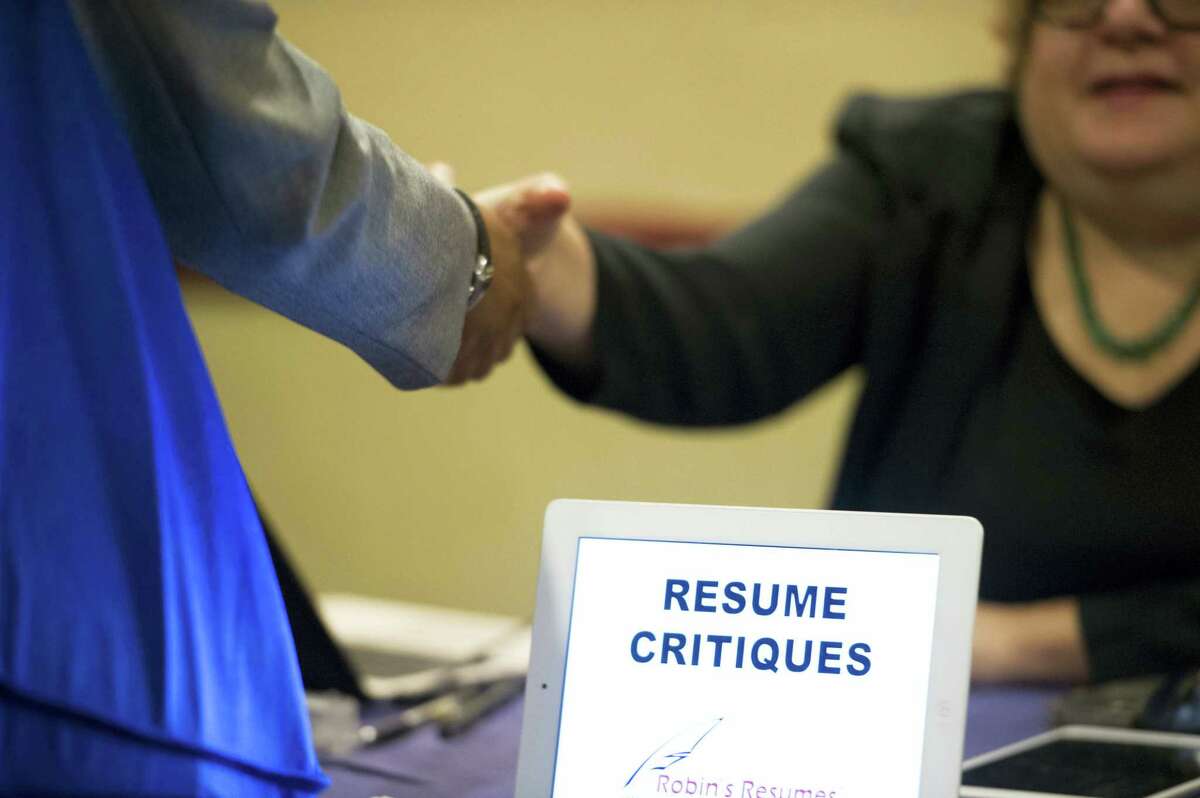 In this Thursday, May 30, 2013, file photo, a job seeker stops at a table offering resume critiques during a job fair held in Atlanta. The Labor Department reported Thursday, Oct. 27, 2016, that fewer Americans sought unemployment aid the week before, a sign that businesses are holding onto their workers and hiring is likely solid.