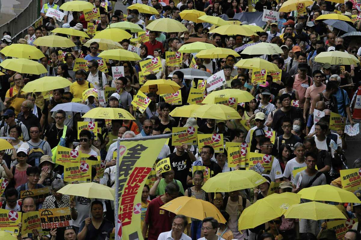Protesters carry yellow umbrellas during a rally as people march in a downtown street to support a veto of the government’s electoral reform package in Hong Kong on June 14, 2015. The rally was held ahead of a crucial vote by lawmakers on Beijing-backed election reforms that sparked huge street protests last year.