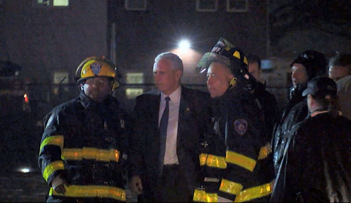 Republican presidential candidate Indiana Gov. Mike Pence talks with firefighters at New York’s LaGuardia Airport after his campaign plane slide off the runway while landing on Thursday, Oct. 27, 2016.