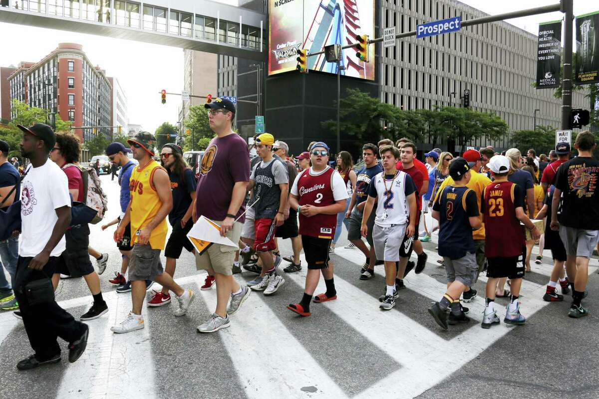 Cleveland Cavalier fans cross the street at the corner of East 9th Street and Euclid to watch a parade celebrating the Cleveland Cavaliers’ NBA Championship in downtown Cleveland Wednesday, June 22, 2016.